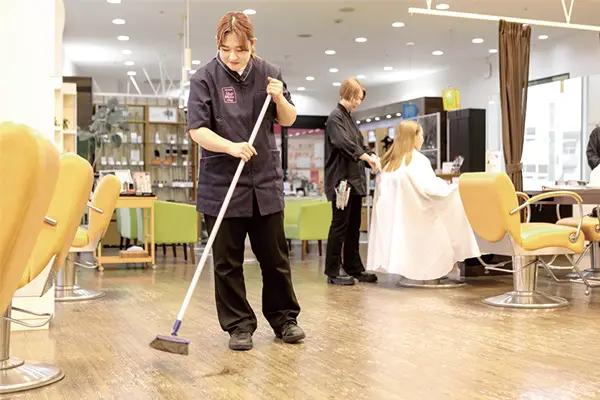 実際のサロンで床の掃き掃除をする学生