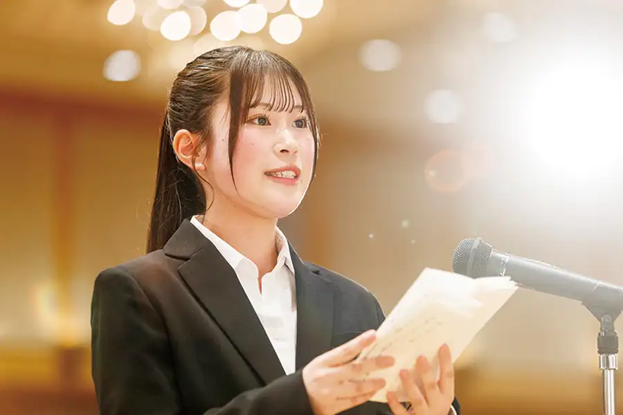 新入生代表挨拶の様子。ステージ上で挨拶文を読む学生