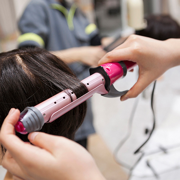 ヘアアイロンを使って髪の毛を巻いている様子