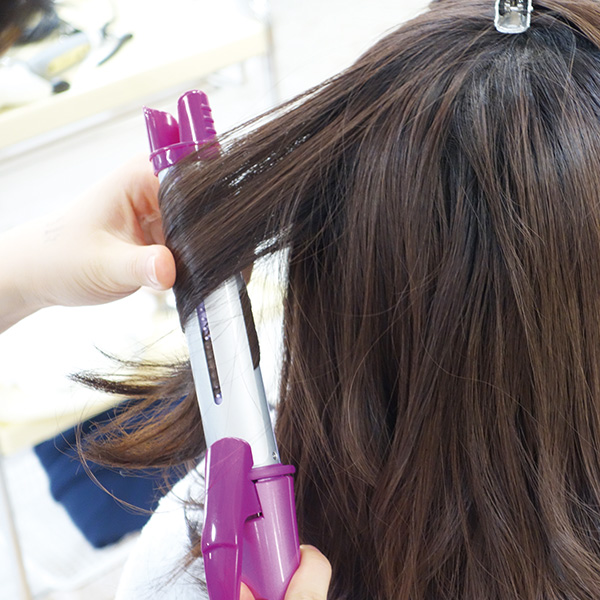 ヘアアイロンで髪の毛を巻いている様子