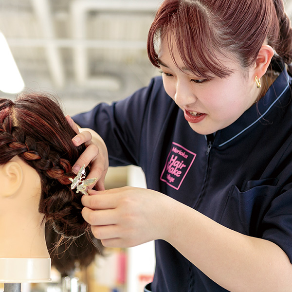 マネキンでヘアアレンジの練習をする学生