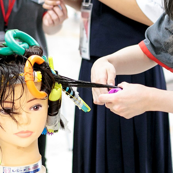 マネキンを使ってパーマの練習をしている写真